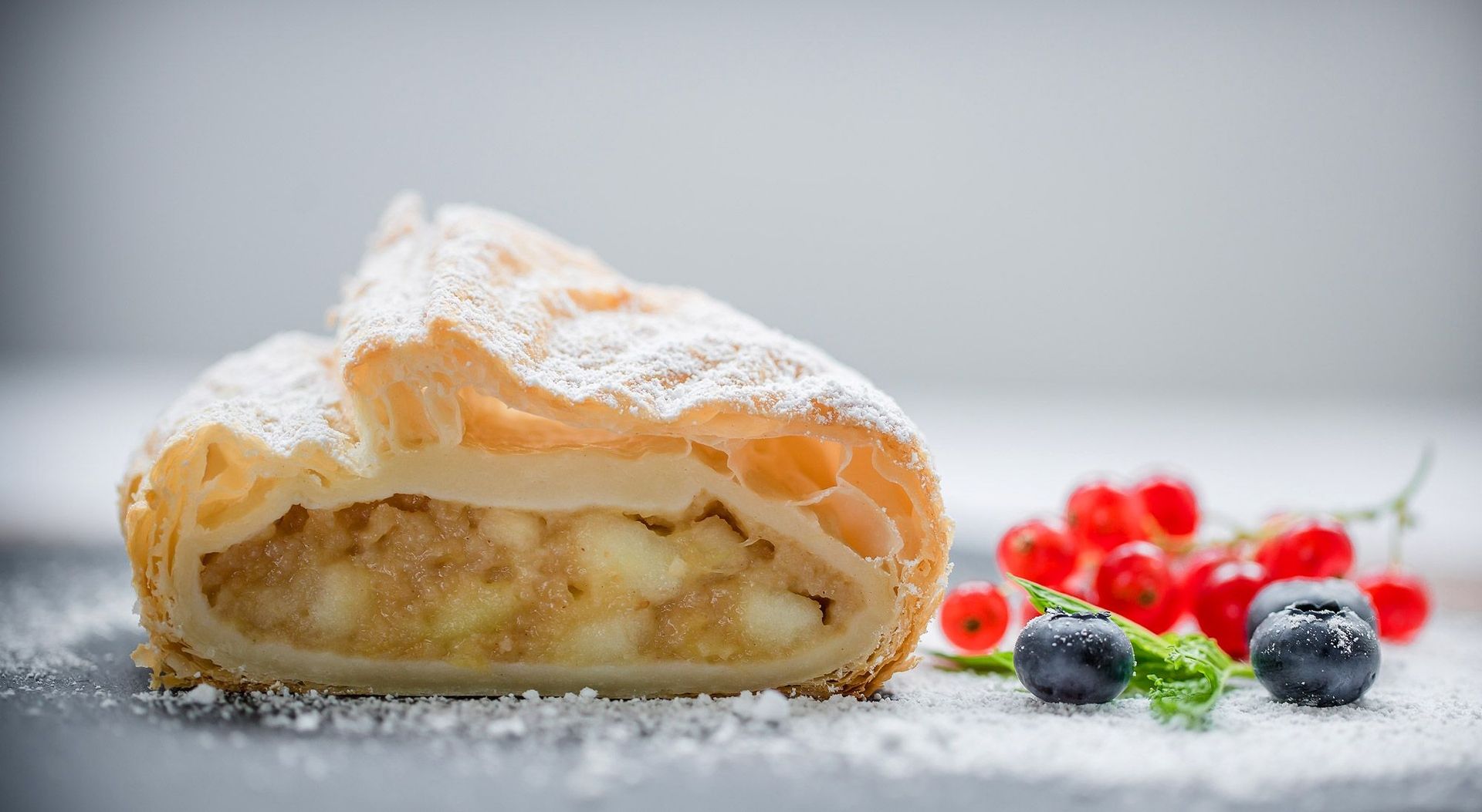 Ein Gebäck mit frischen Beeren und Puderzucker bestreut.