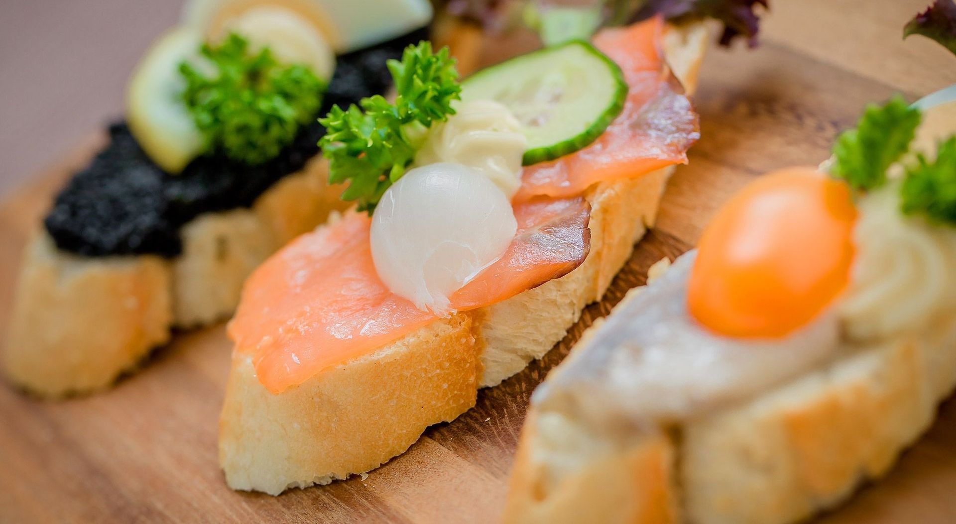 Ein Holzbrett mit vier verschiedenen Arten von Lebensmitteln, darunter Käse, Obst, Wurst und Brot.